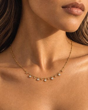 Close-up of Aurevia Necklace on model featuring polished golden spheres and subtle crystal accents