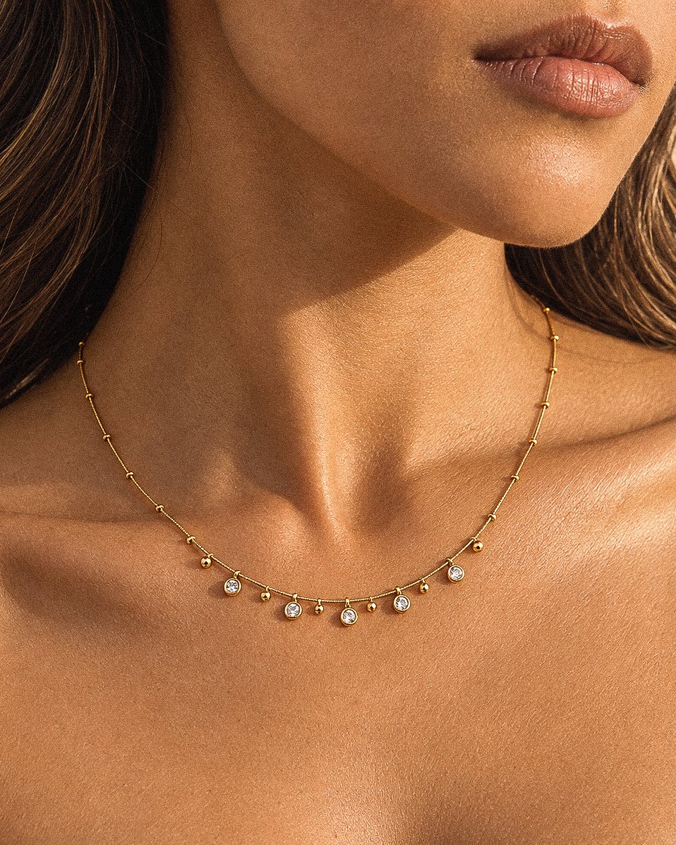 Close-up of Aurevia Necklace on model featuring polished golden spheres and subtle crystal accents