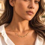 Side-angle view of a model wearing Aurevia Necklace with small golden spheres and crystal accents