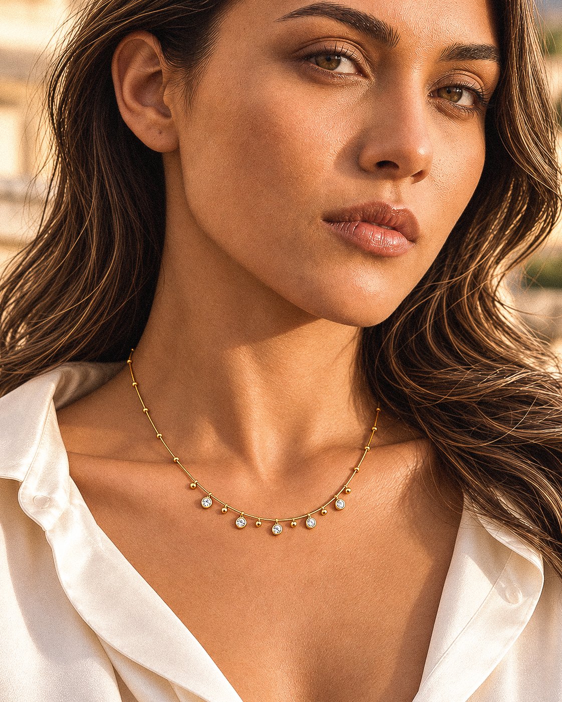 Side-angle view of a model wearing Aurevia Necklace with small golden spheres and crystal accents