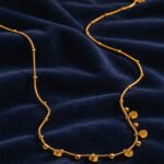 Aurevia Necklace laid flat on a clean background showing polished golden spheres and subtle crystal accents