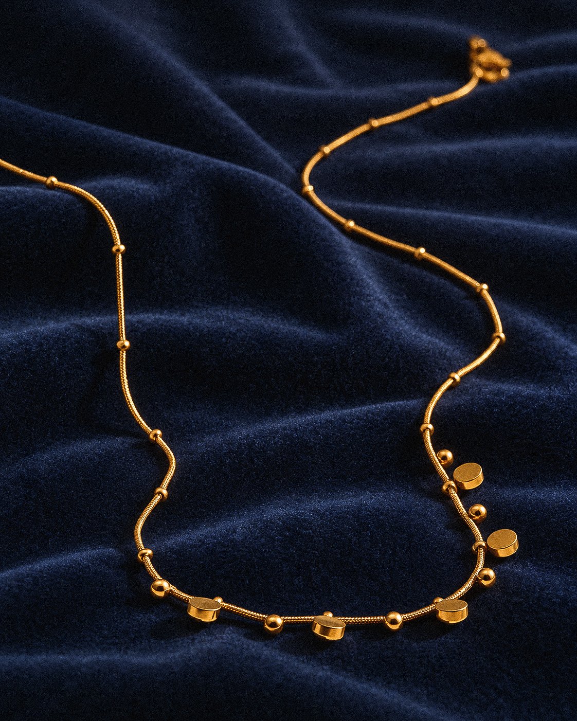 Aurevia Necklace laid flat on a clean background showing polished golden spheres and subtle crystal accents