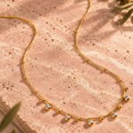 Close-up product image of Aurevia Necklace showing polished gold spheres and delicate crystal accents