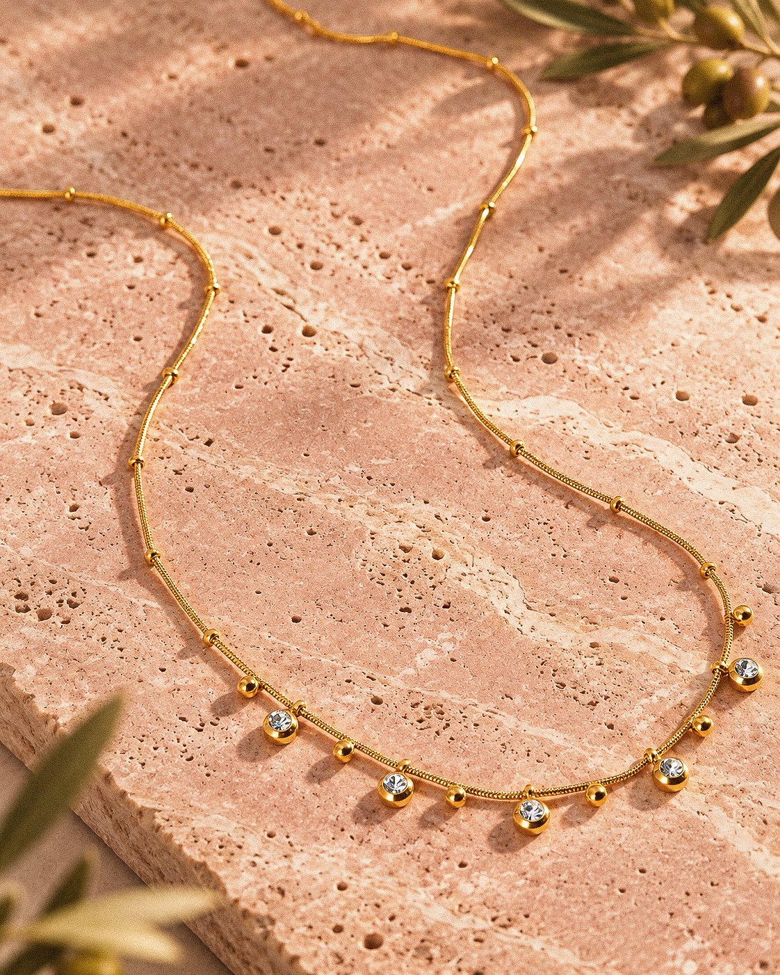 Close-up product image of Aurevia Necklace showing polished gold spheres and delicate crystal accents