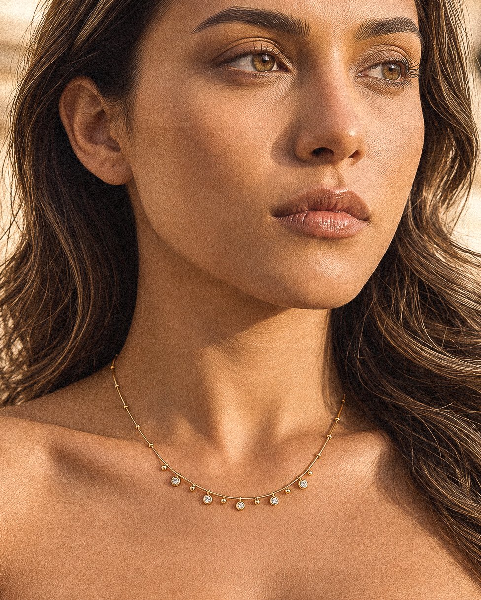 Woman wearing Aurevia Necklace, a delicate gold necklace with polished golden spheres and subtle crystal accents