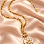 Flat lay of Avelora Necklace showing its elegant gold and silver-toned ring pattern on a neutral background