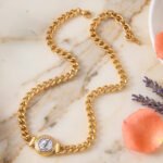 Eterna Eleganza Necklace on marble background with polished gold necklace design
