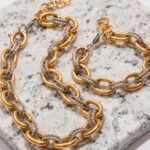 Flat lay of Regia Trama Collection on marble background showing necklace and bracelet set