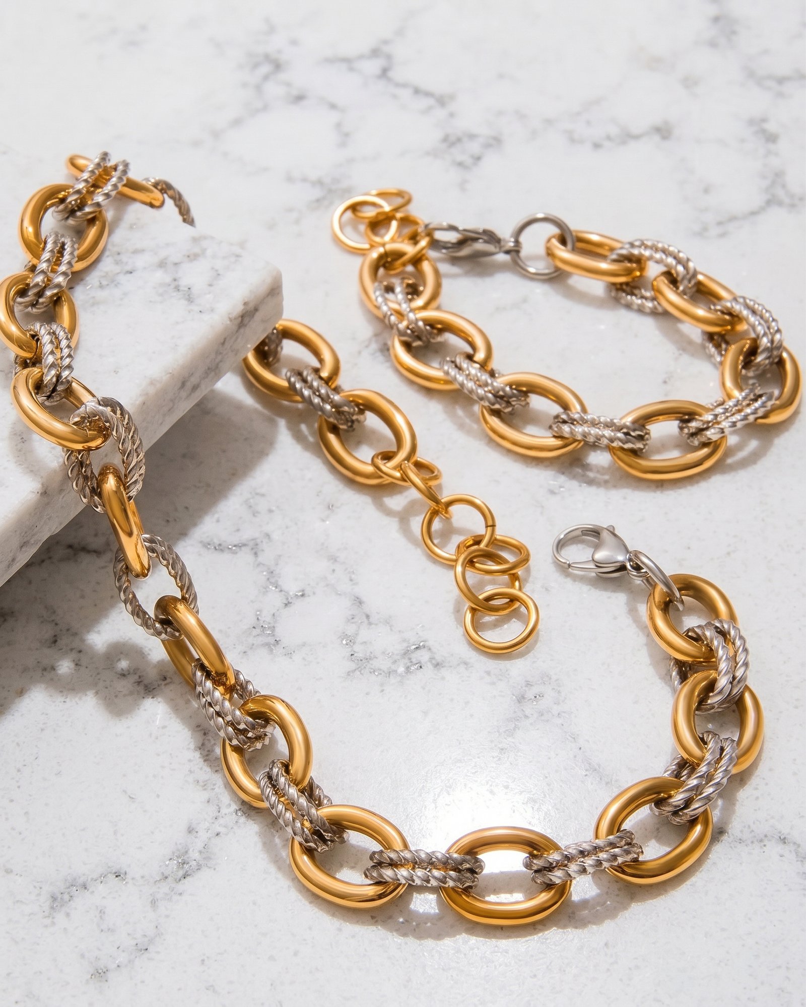 Regia Trama Collection displayed on marble background with necklace and bracelet