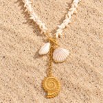 Flat lay of Marina Alba Necklace with white shell-inspired beads and sea-inspired gold charms
