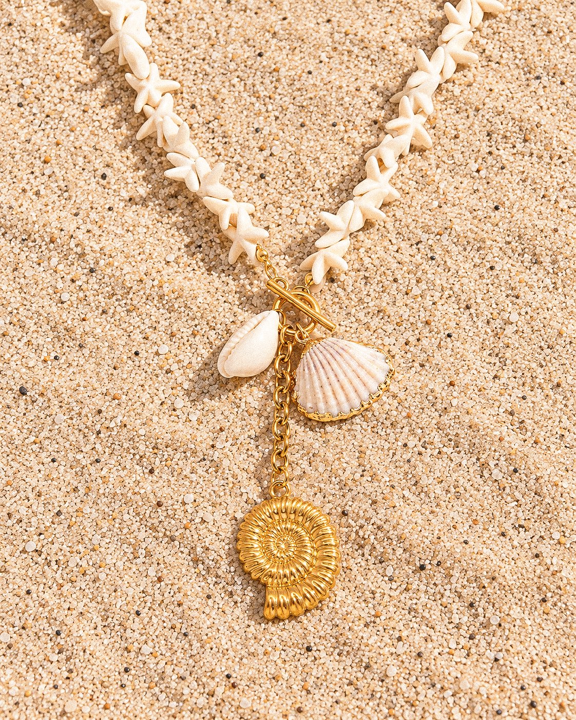 Flat lay of Marina Alba Necklace with white shell-inspired beads and sea-inspired gold charms