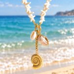 Marina Alba Necklace displayed on a sea-inspired background with white shell-inspired beads and gold sea charms