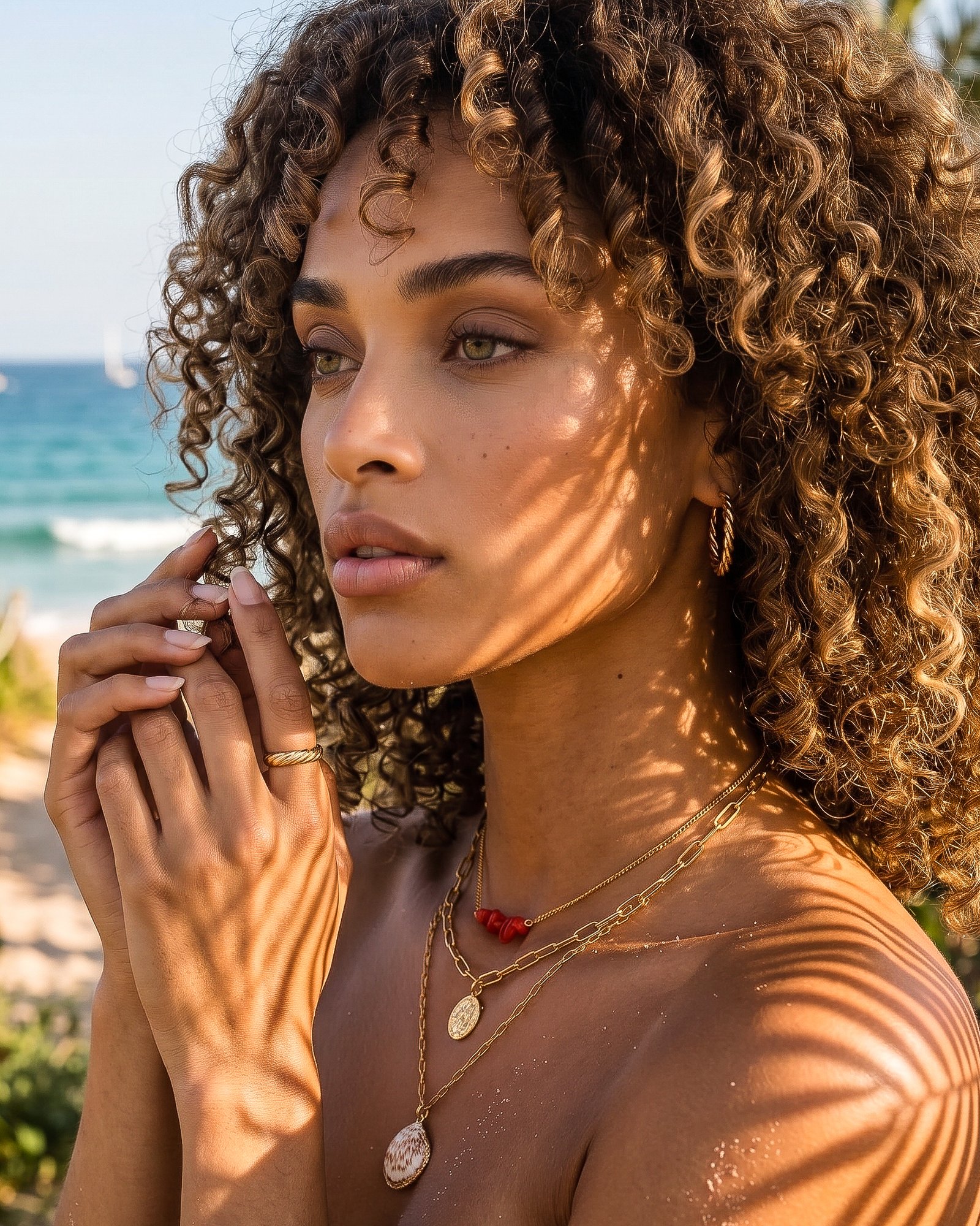 Side-angle view of model wearing Seravelle Necklace with red bead chain, coin charm, and shell pendant