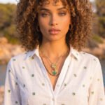 Elegant portrait of woman wearing Veralia Duo Necklace with green clover and gold pendant details