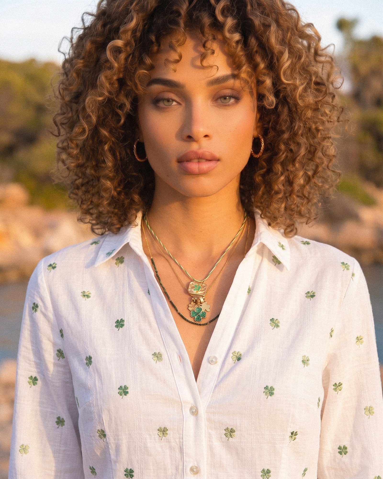 Elegant portrait of woman wearing Veralia Duo Necklace with green clover and gold pendant details