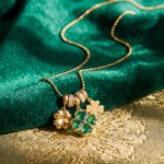 Flat lay of Veralia Duo Necklace with green beads golden clover charms and pendant details