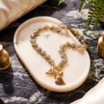 Ambralia Necklace flat lay with smoky heart beads and gold toggle necklace design