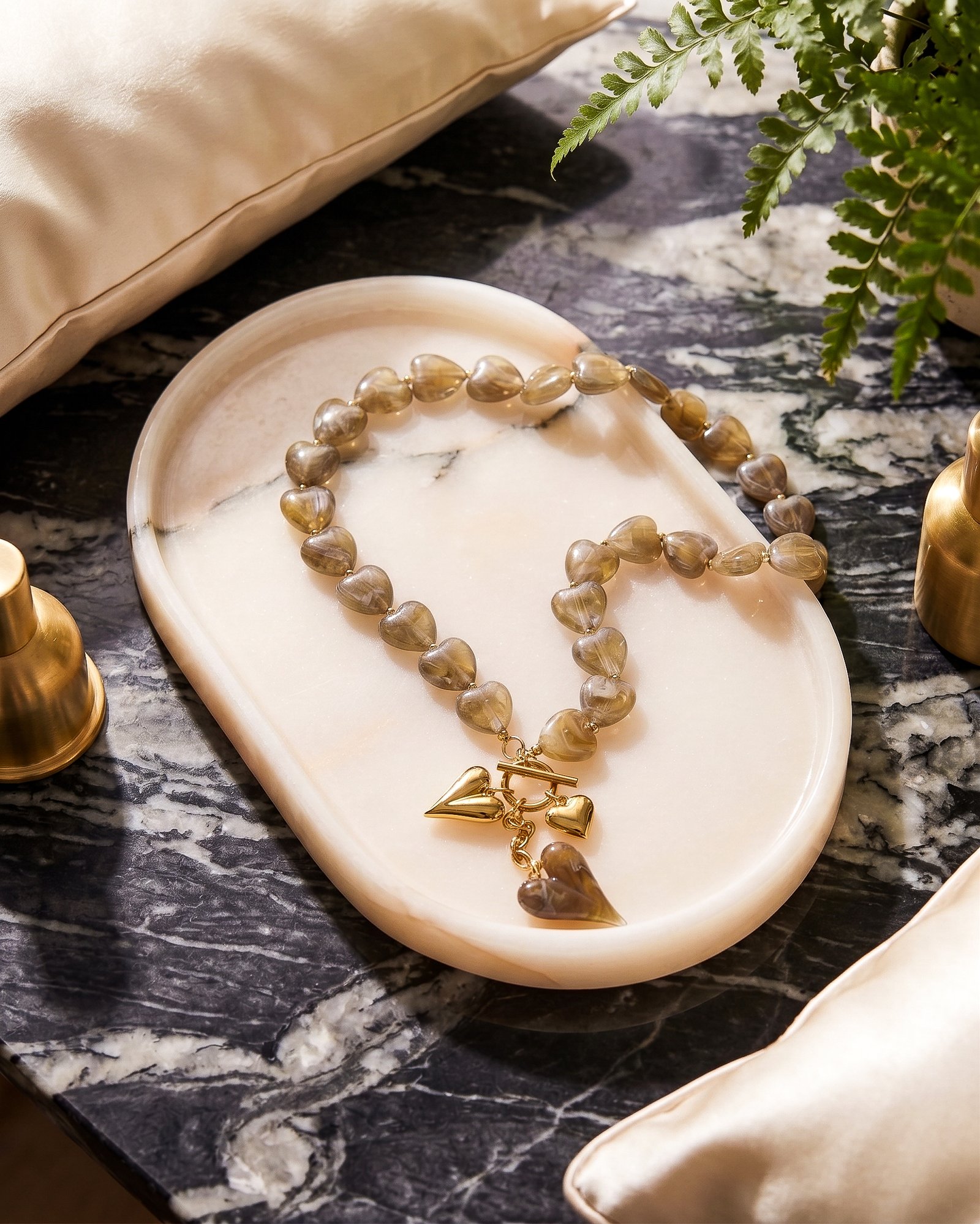 Ambralia Necklace flat lay with smoky heart beads and gold toggle necklace design