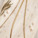Elvara Necklace styled on a soft luxury background with layered gold chains