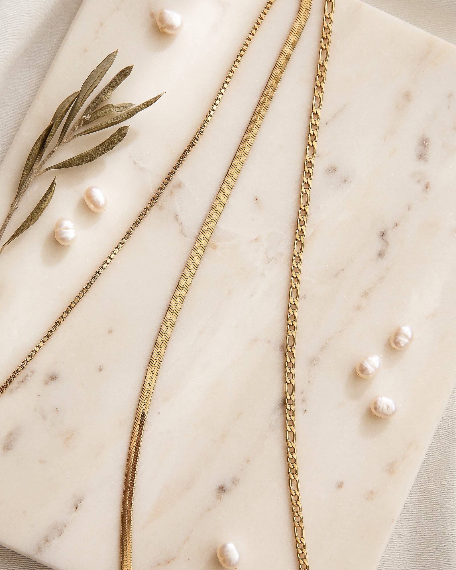 Elvara Necklace styled on a soft luxury background with layered gold chains