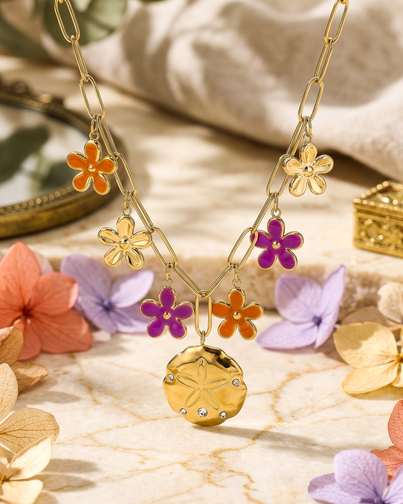 Close-up product image of Fiori Solari Necklace showing colorful flower charms, gold paperclip links, and central medallion detail