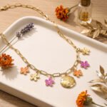 Fiori Solari Necklace displayed on a neutral background, featuring a gold plated paperclip chain and colorful flower charms