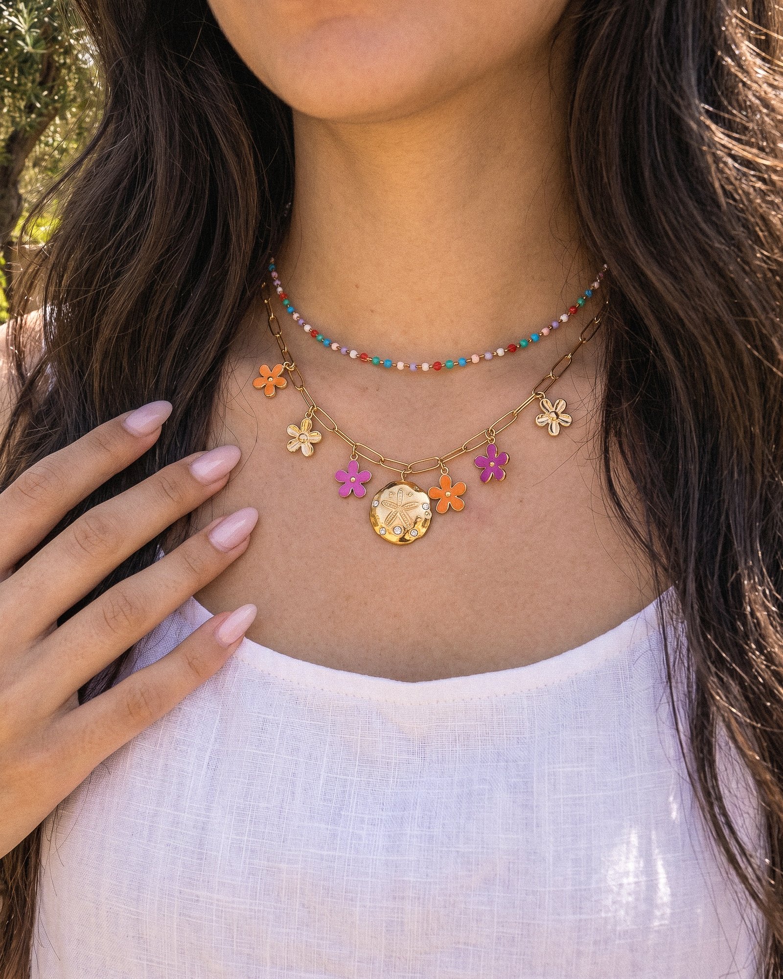 Close-up of Fiori Solari Necklace on a model, showing the gold chain, colorful flower charms, and decorative medallion detail