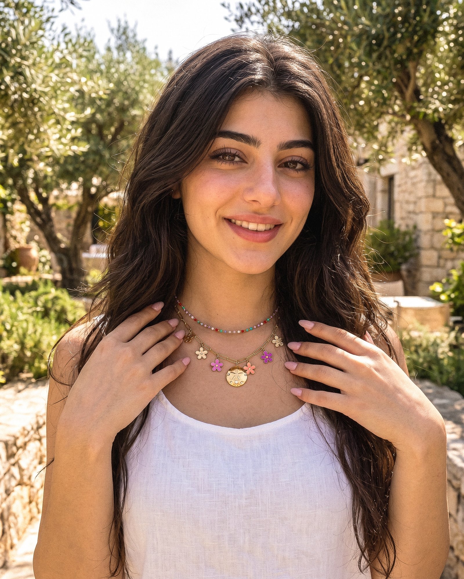 Fiori Solari Necklace worn by a model, featuring a gold paperclip chain with colorful floral charms and a central medallion pendant