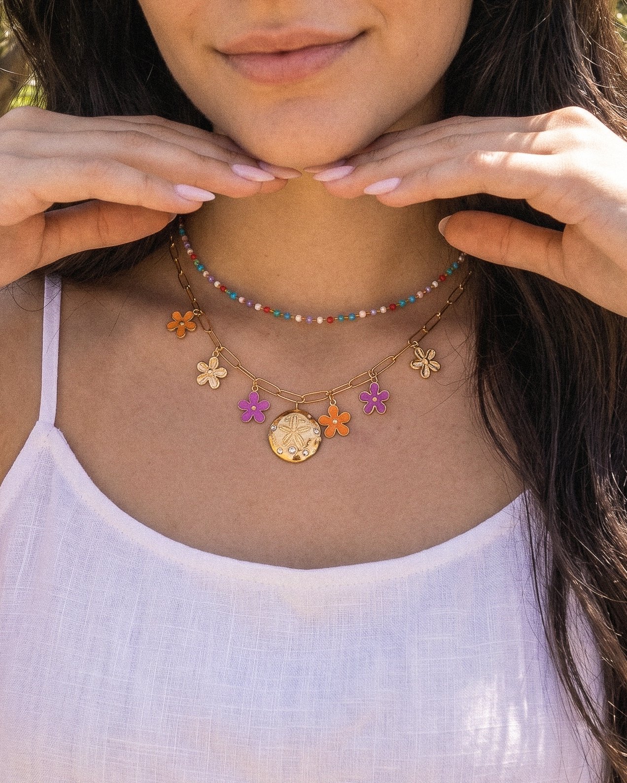 Detailed neckline shot of Fiori Solari Necklace on a model, featuring orange, purple, and gold flower charms