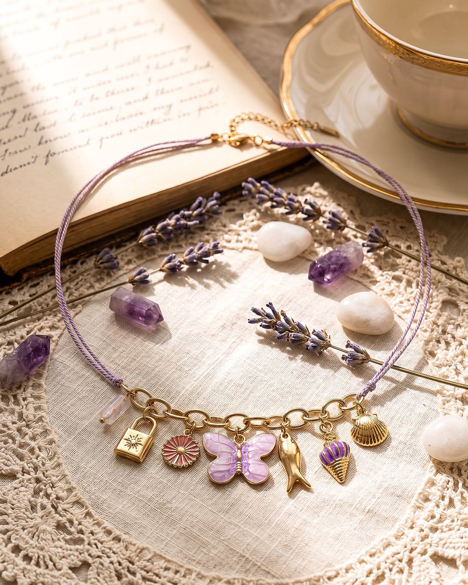 Flat lay of Lunella Charm Necklace with lilac braided cord and gold charm details