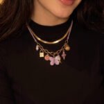 Close-up of Lunella Charm Necklace on model showing butterfly and charm details