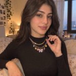 Female model wearing Lunella Charm Necklace with decorative charms in a close neckline shot