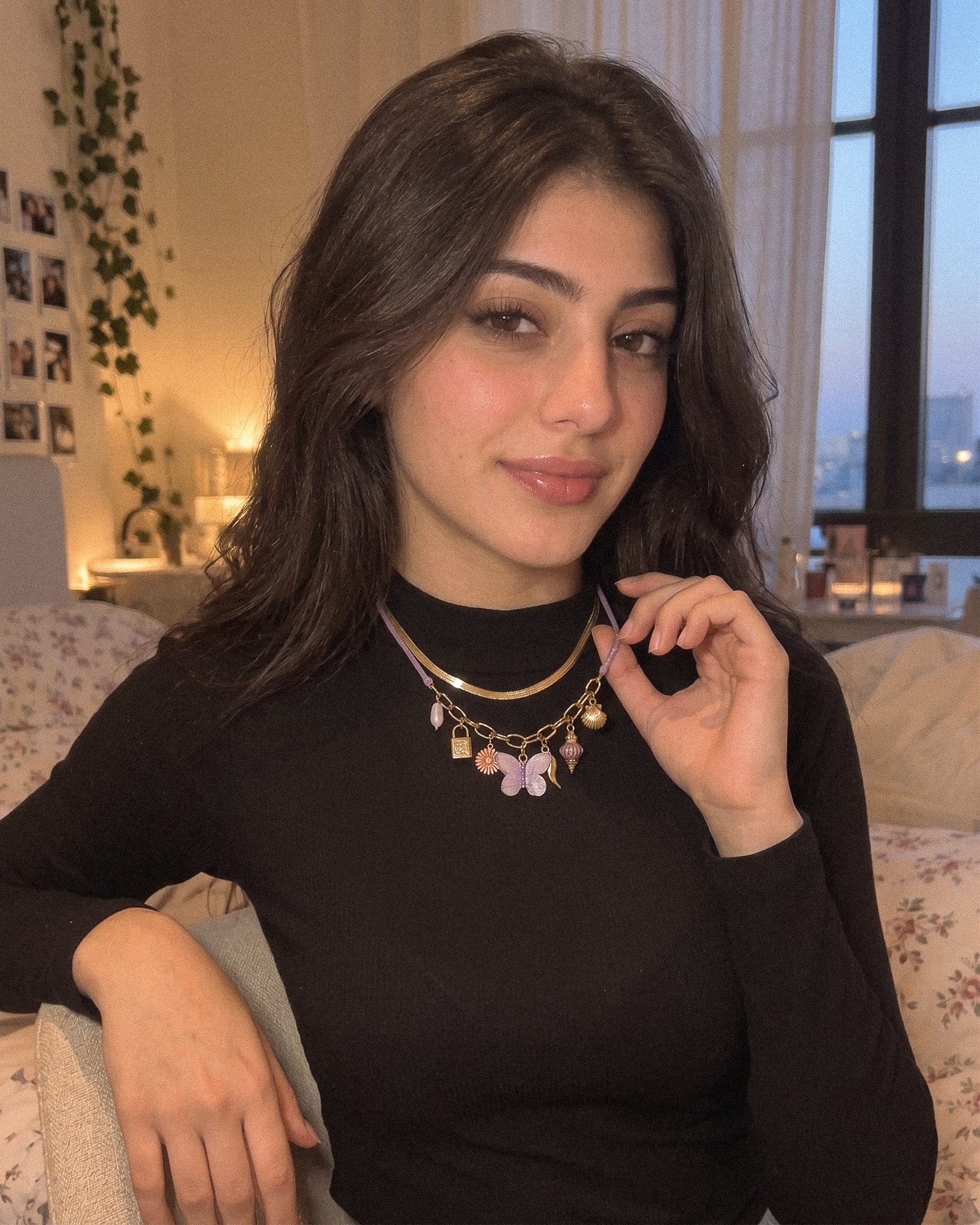 Female model wearing Lunella Charm Necklace with decorative charms in a close neckline shot