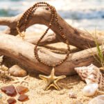 Stella Terra necklace from Mare Amuleti Necklaces on background with brown beads and gold starfish charm
