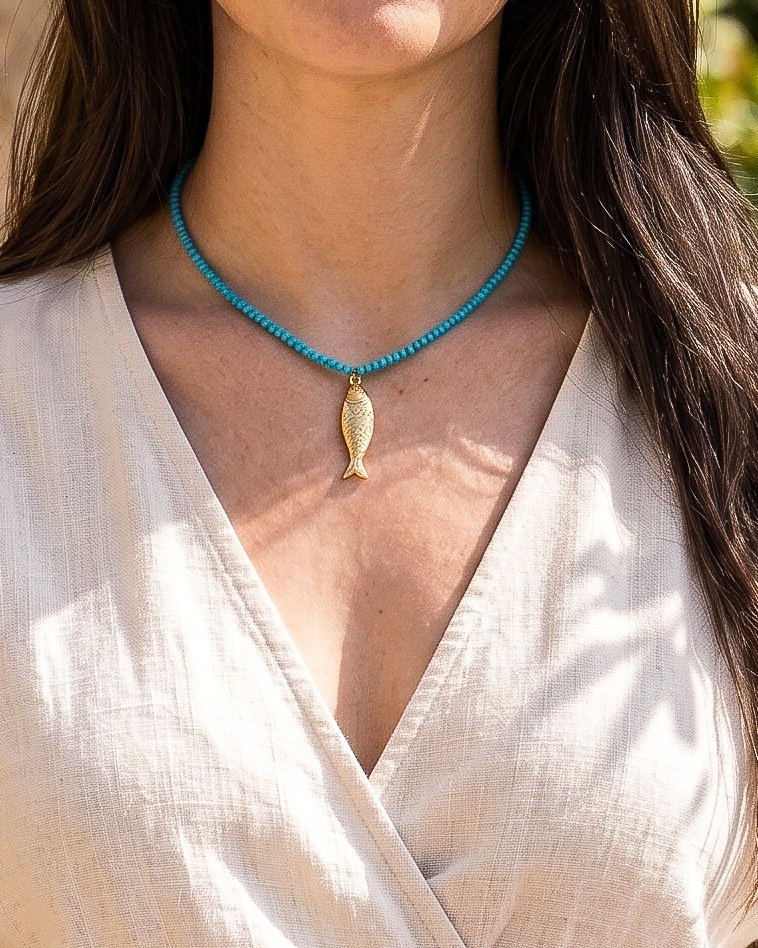 Model wearing Pesce Azzurro from Mare Amuleti Necklaces, featuring turquoise beads and a gold fish charm