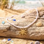 Sole Bianco necklace from Mare Amuleti Necklaces on background with white beads and gold sun charm