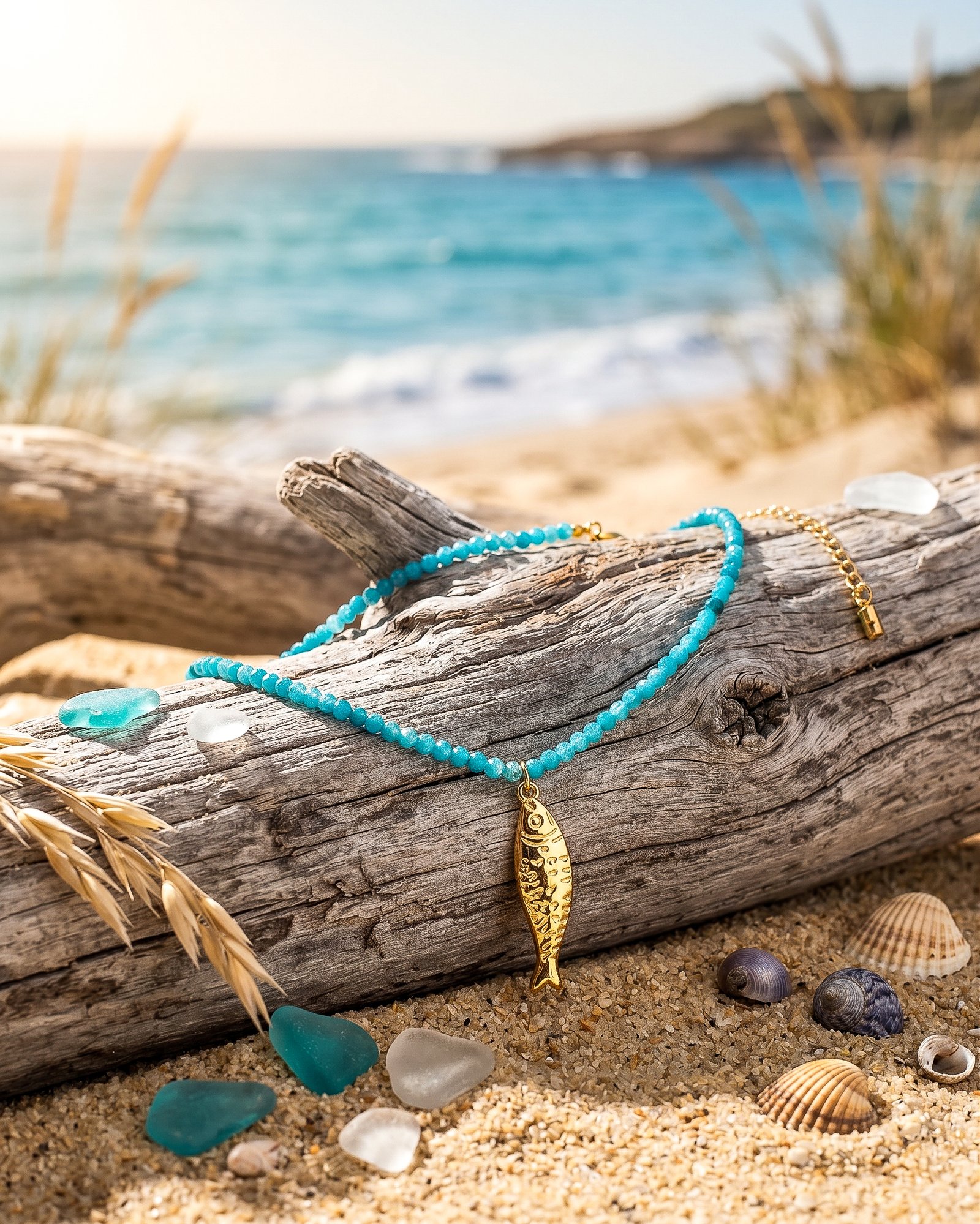 Pesce Azzurro necklace from Mare Amuleti Necklaces on background with turquoise beads and gold fish charm