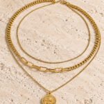 Valessia Necklace displayed on a stone background showing the layered gold chain design