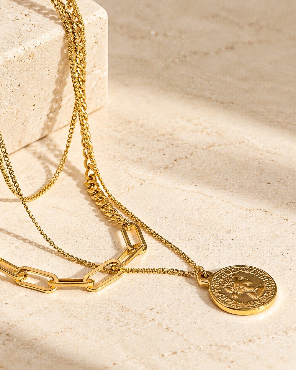 Valessia Necklace detailed product image on stone background showing the coin charm